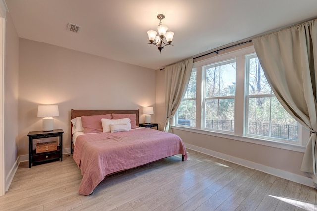 bedroom with a chandelier, baseboards, visible vents, and light wood-style flooring