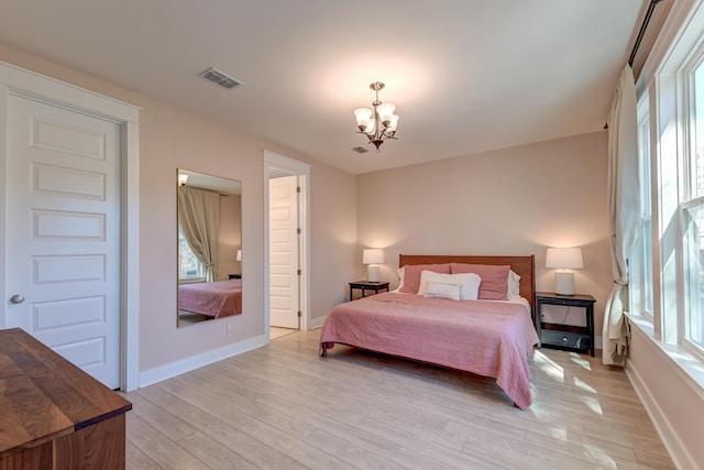 bedroom with visible vents, baseboards, light wood-style flooring, and a chandelier