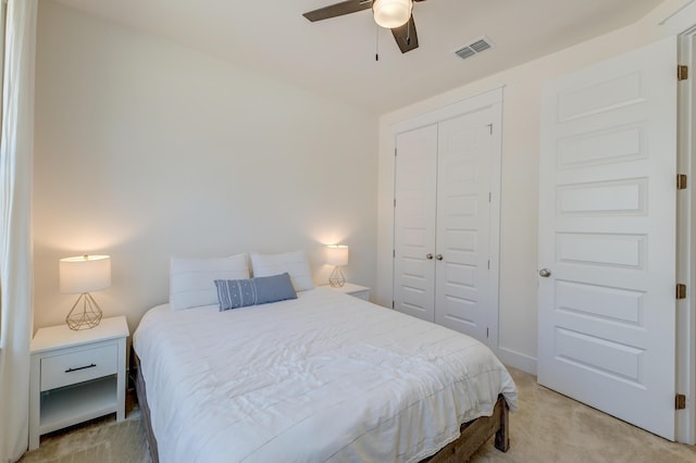 bedroom with visible vents, light colored carpet, a closet, and ceiling fan