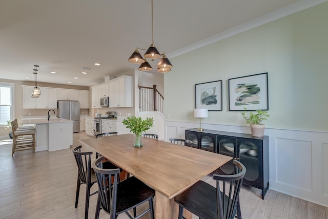 dining space with recessed lighting, ornamental molding, wainscoting, and light wood finished floors