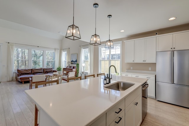 kitchen featuring pendant lighting, a sink, stainless steel appliances, light wood finished floors, and light countertops