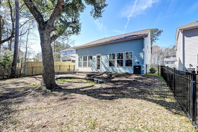 rear view of property featuring central AC unit and a fenced backyard