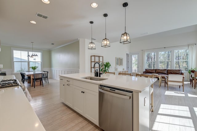 kitchen with a wainscoted wall, visible vents, a sink, dishwasher, and open floor plan