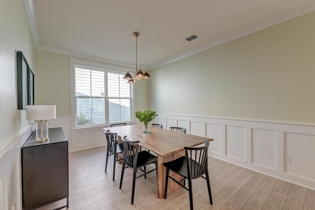 dining area featuring visible vents, ornamental molding, and light wood finished floors