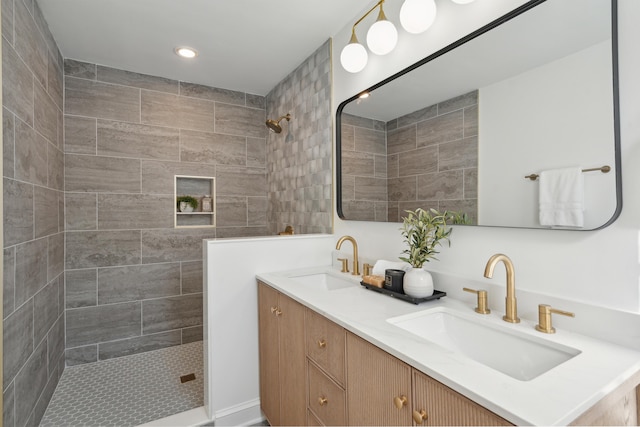 bathroom featuring a tile shower, recessed lighting, double vanity, and a sink