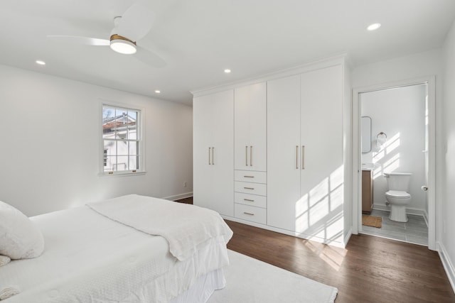 bedroom with dark wood-style floors, recessed lighting, baseboards, and connected bathroom