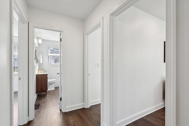 corridor featuring dark wood-style floors, visible vents, and baseboards