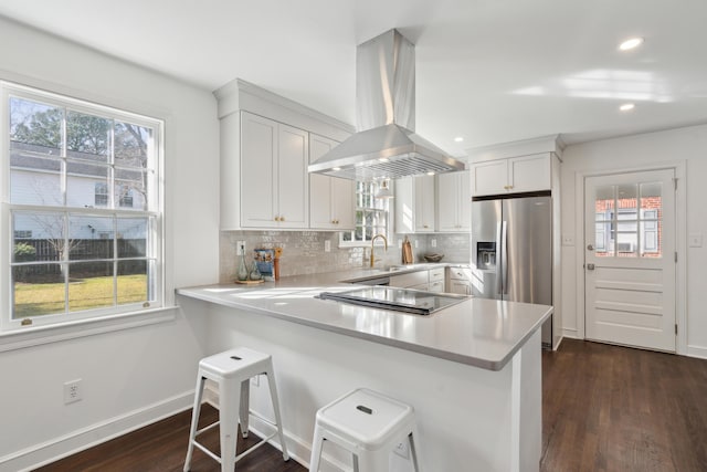 kitchen featuring backsplash, stainless steel fridge, island exhaust hood, and light countertops