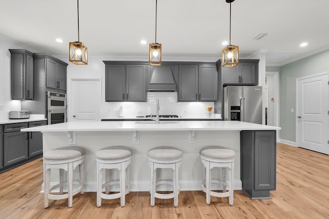 kitchen with pendant lighting, a kitchen island with sink, and custom exhaust hood