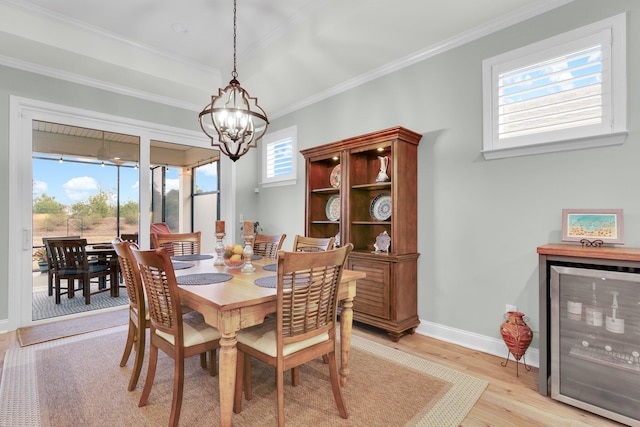 dining area with light hardwood / wood-style floors, crown molding, and beverage cooler