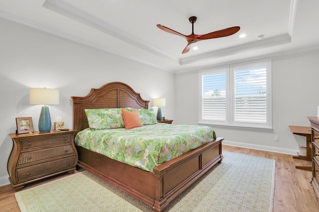 bedroom featuring ceiling fan, light hardwood / wood-style floors, a raised ceiling, and crown molding