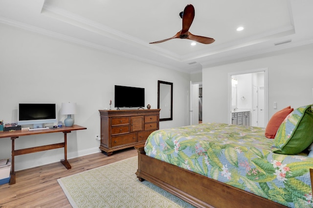 bedroom featuring a tray ceiling, ceiling fan, and ensuite bathroom