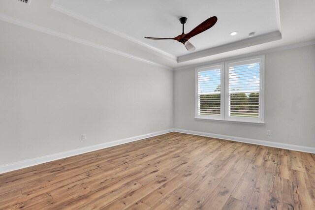 unfurnished room with baseboards, a raised ceiling, a ceiling fan, crown molding, and wood-type flooring