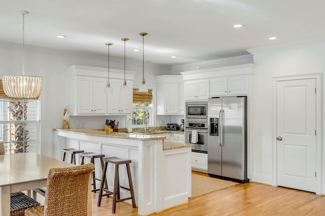 kitchen featuring stainless steel appliances, light wood-type flooring, a peninsula, and white cabinetry