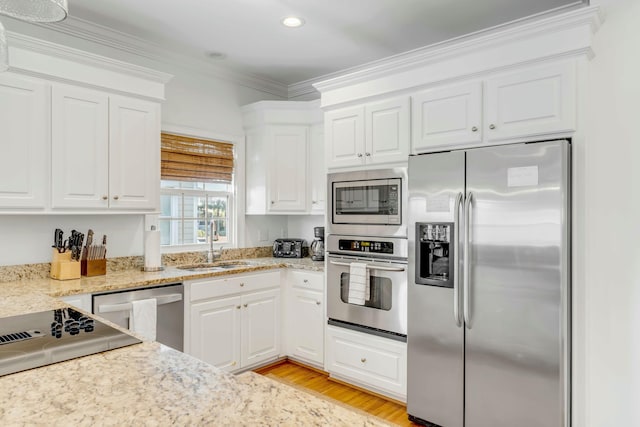 kitchen with stainless steel appliances, ornamental molding, a sink, and white cabinets