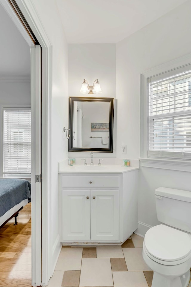 bathroom with toilet, ornamental molding, vanity, tile patterned flooring, and baseboards