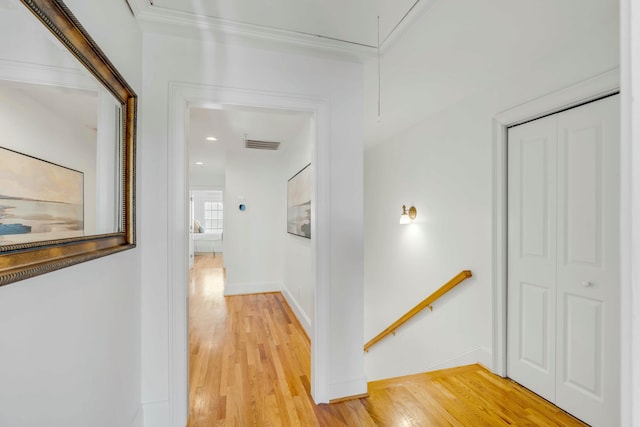 hallway featuring visible vents, an upstairs landing, baseboards, light wood-type flooring, and attic access