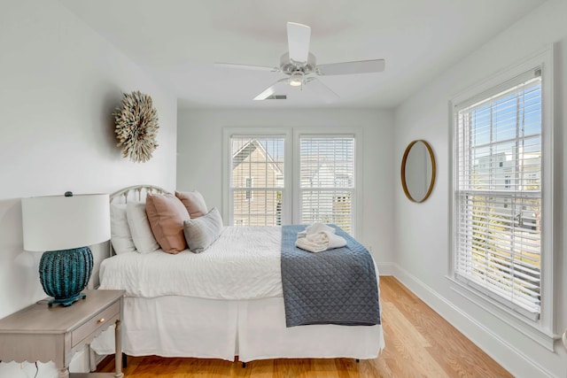 bedroom with ceiling fan, light wood finished floors, visible vents, and baseboards