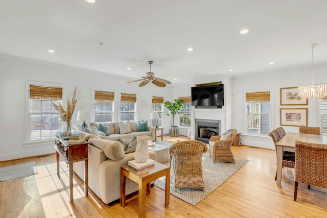 living room featuring light wood-type flooring, a wealth of natural light, a fireplace, and recessed lighting