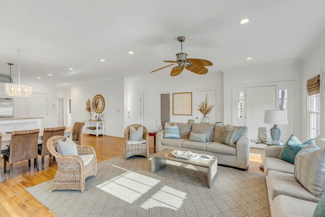 living room with light wood-style flooring, ceiling fan with notable chandelier, and recessed lighting