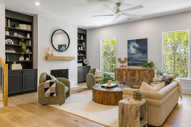 living room featuring ceiling fan, built in features, and light hardwood / wood-style floors