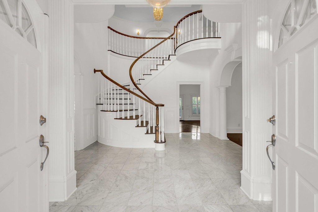 foyer featuring a towering ceiling and decorative columns