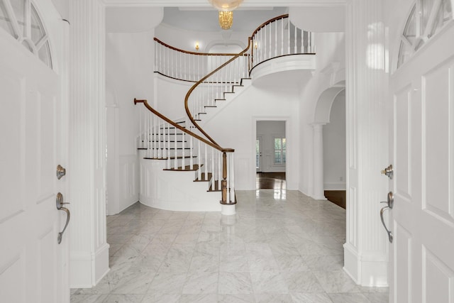 foyer featuring a towering ceiling and decorative columns