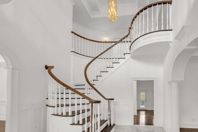 stairway with ornamental molding, a high ceiling, and decorative columns