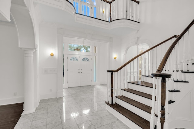 entrance foyer featuring decorative columns, a high ceiling, and ornamental molding