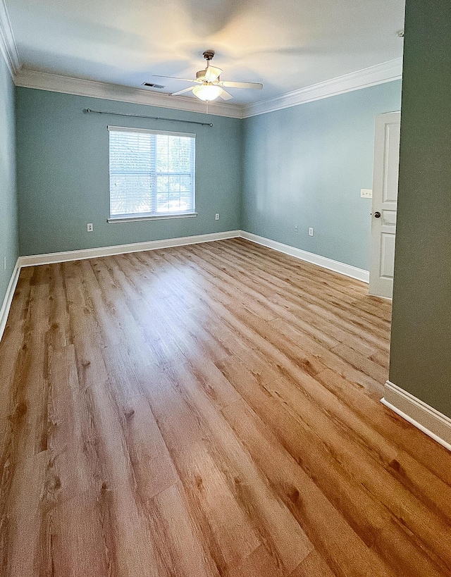 unfurnished room with visible vents, ornamental molding, ceiling fan, wood finished floors, and baseboards