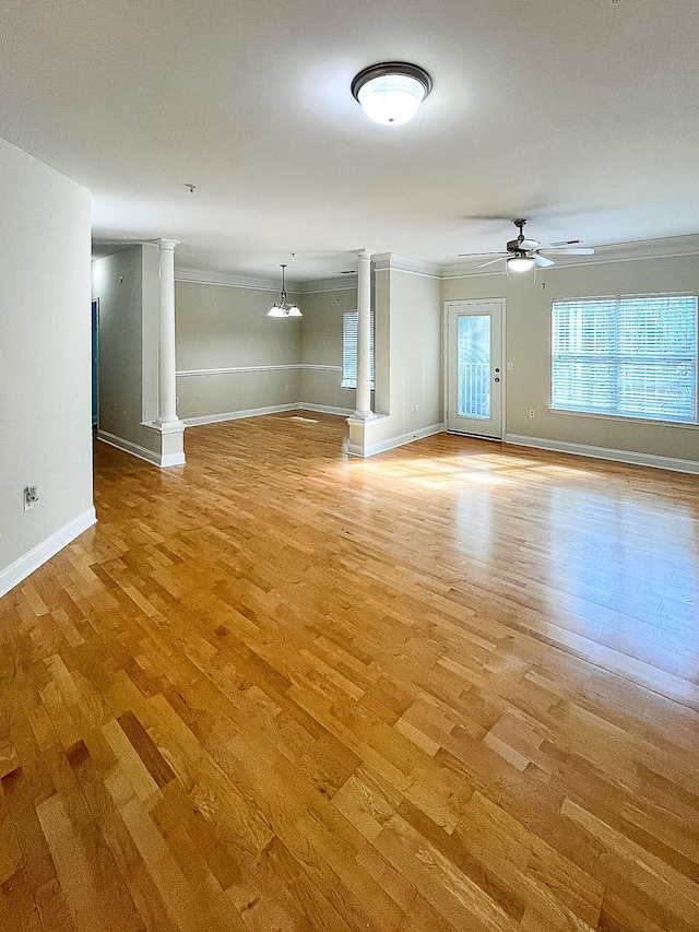 unfurnished living room with ornate columns, a ceiling fan, ornamental molding, and light wood-style floors