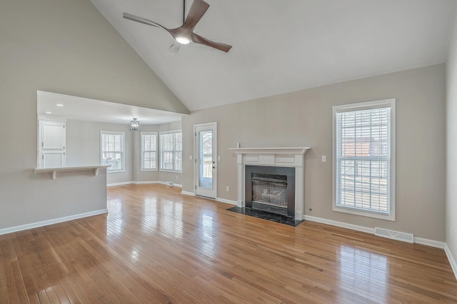 unfurnished living room with light wood finished floors, visible vents, a fireplace with flush hearth, a ceiling fan, and baseboards