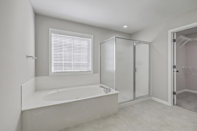 bathroom with a garden tub, a shower stall, baseboards, and a spacious closet