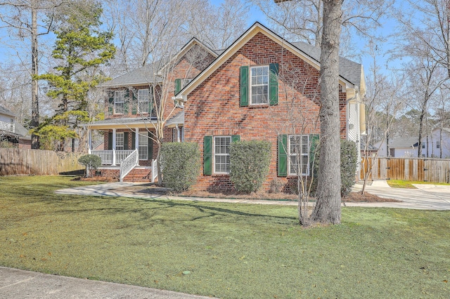 view of front of property featuring brick siding, a shingled roof, covered porch, fence, and a front lawn