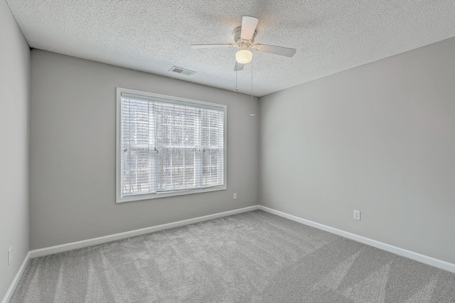 empty room featuring baseboards, visible vents, a ceiling fan, carpet, and a textured ceiling