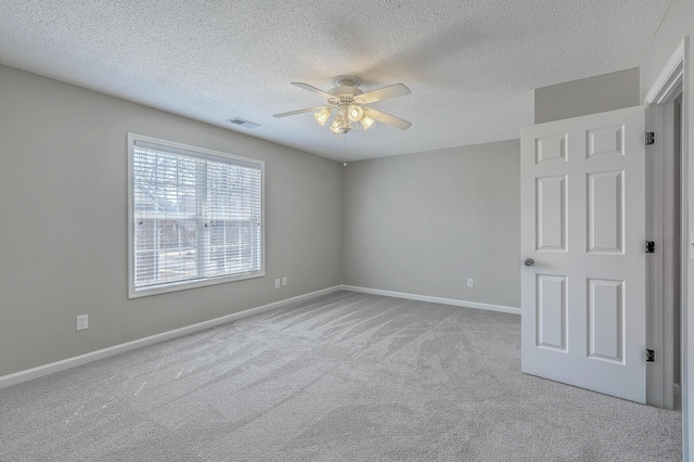 spare room with ceiling fan, a textured ceiling, visible vents, baseboards, and carpet