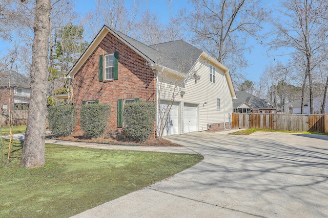 view of home's exterior featuring a shingled roof, concrete driveway, fence, a yard, and brick siding