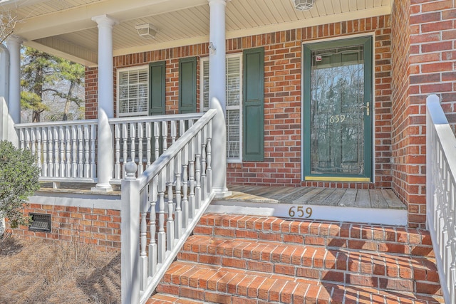 entrance to property with a porch and brick siding