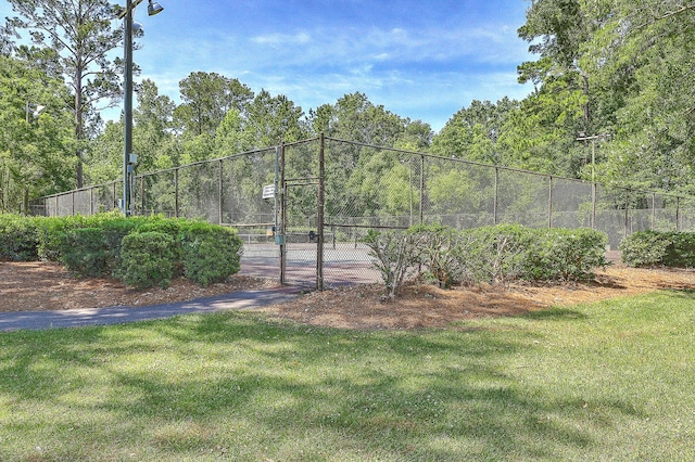 view of sport court featuring a gate, fence, and a yard