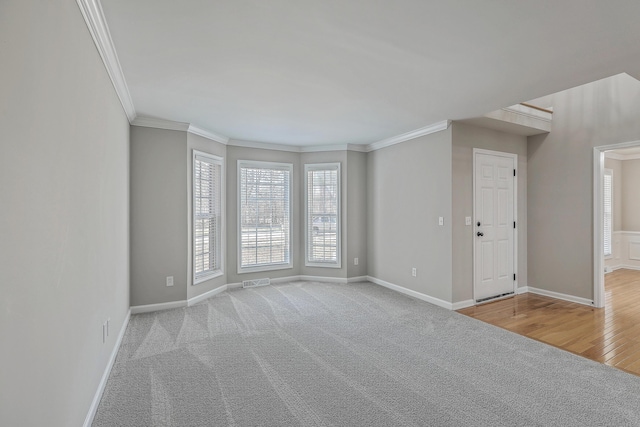 carpeted empty room with baseboards, visible vents, and crown molding