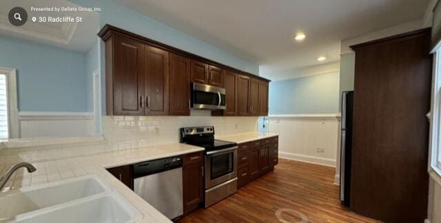 kitchen with decorative backsplash, appliances with stainless steel finishes, dark brown cabinetry, sink, and dark hardwood / wood-style floors