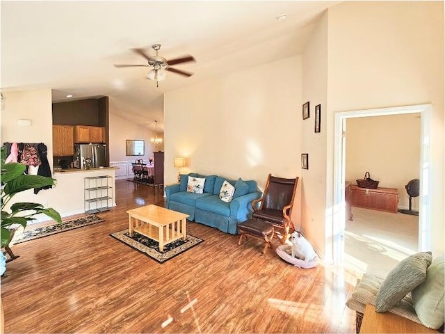 living area featuring ceiling fan with notable chandelier, lofted ceiling, and wood finished floors