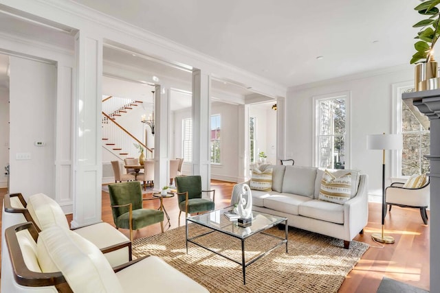 living room featuring ornamental molding, wood finished floors, decorative columns, and stairs