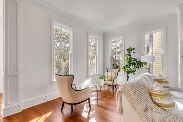 sitting room featuring baseboards, wood finished floors, and crown molding