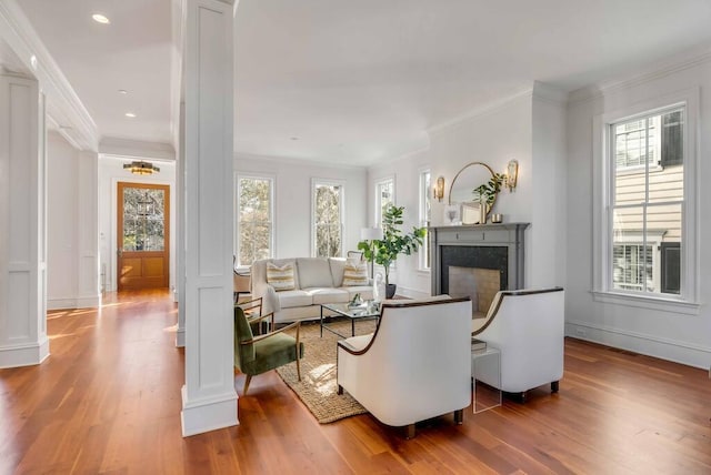 living room with ornamental molding, a fireplace, ornate columns, and wood finished floors