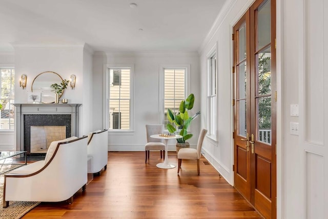 sitting room featuring baseboards, wood finished floors, a high end fireplace, and crown molding