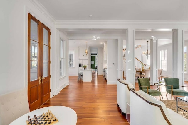 entryway with light wood-style flooring, stairway, ornamental molding, an inviting chandelier, and ornate columns