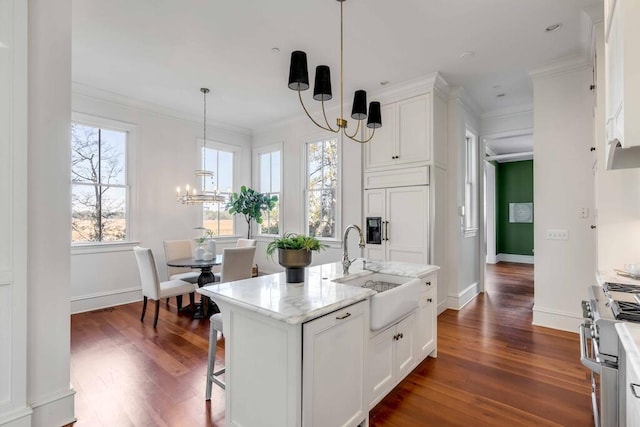 kitchen with premium appliances, a notable chandelier, a center island with sink, hanging light fixtures, and white cabinets