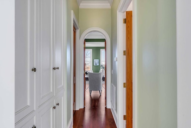 corridor featuring arched walkways, dark wood finished floors, visible vents, and crown molding