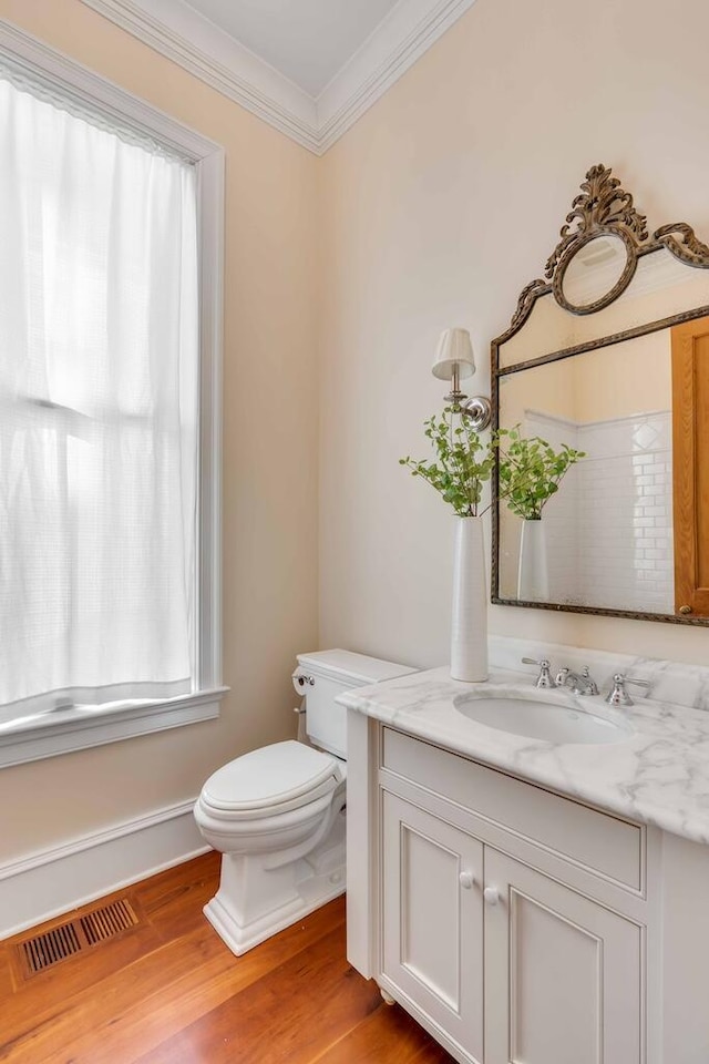 bathroom with toilet, wood finished floors, vanity, visible vents, and ornamental molding